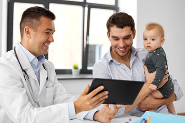 medicine, healthcare, pediatry and people concept - happy doctor showing tablet computer to father...