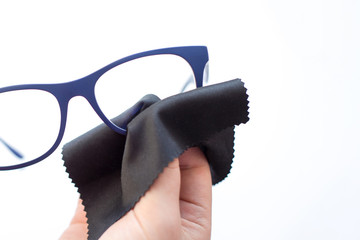 female hands wiping spectacles with a microfiber fabric