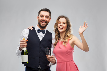 celebration and people concept - happy couple with bottle of champagne and glasses over grey background