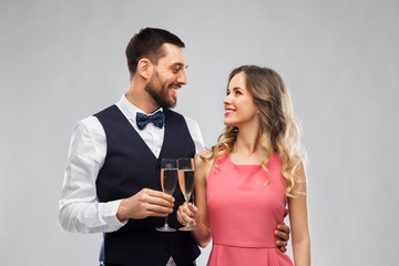 celebration and people concept - happy couple with champagne glasses toasting over grey background