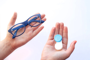 female hands holding spectacles and contact lenses and choosing