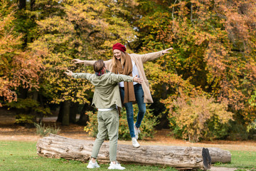 Fototapeta premium junge Frau lässt sich zu ihrem Freund fallen, er fängt sie auf, im herbstlichen Park