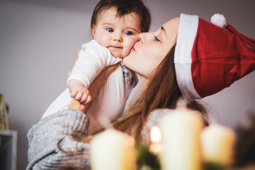 mom with santa hat kissing her baby at christmas time