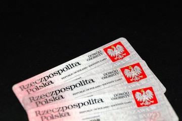 Selective focus. Polish Identity Cards, with Coat of arms of Poland (white, crowned eagle on a red background). Translation of description: Republic of Poland, Identity Card. Black background