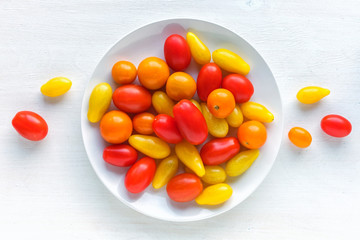 Red and yellow tomatoes on white table
