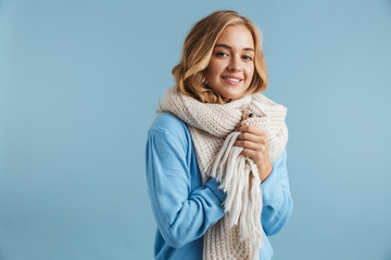 Image of blond woman 20s wrapped in scarf smiling at camera, isolated over blue background
