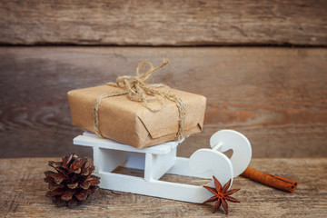 Christmas New Year composition winter objects gift box pine cone balls candle and sled on old shabby rustic wooden background. Xmas holiday december decoration copy space. Time for celebration