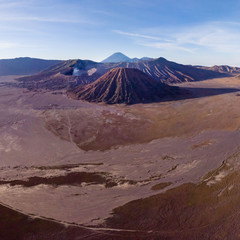 Naklejka premium Mount Bromo volcano crater erupts in the caldera, behind Gunung Batok, with Gunung Semeru in the background, Java, Indonesia.