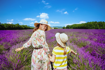 mother and child against lavender field touching lavender