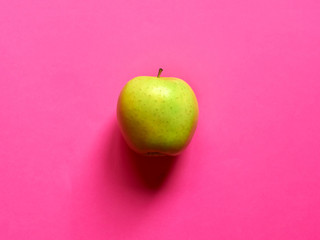 Above view of a Green apple isolated in a fuscia background in studio