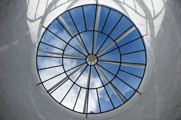 Round roof window with a view of the sky and clouds