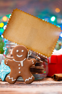 Gingerbread Christmas cookies and blank paper sheet on wooden table