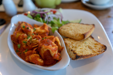 Italian dumplings in a tomato sauce with garlic bread. Food in the restaurant with a bokeh effect.