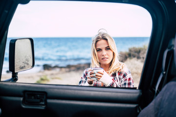 Attractive young millennial blonde take a break outside of her off road car while travel and...