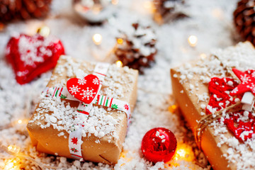 Christmas and New Year background with presents, ribbons, balls and different decorations on snow. Present packed in craft paper with heart, symbol of love.