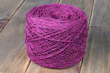 A string of purple knitting yarn. Wooden background. Front view.