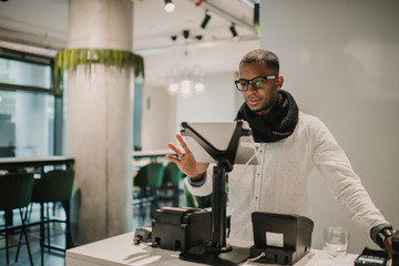 Stylish black man using cash register