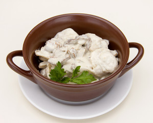 dumplings in a pot with sour cream sauce on a white background