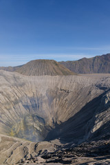 Mount Bromo volcano crater erupts in the caldera, behind Gunung Batok, with Gunung Semeru in the background, Java, Indonesia.