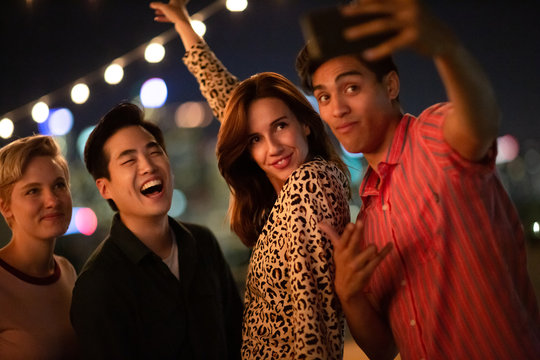 Group of friends taking selfie at an outdoor party at night