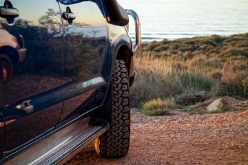 A blue modern SUV with off-road tyres parked near the ocean in Western Australia
