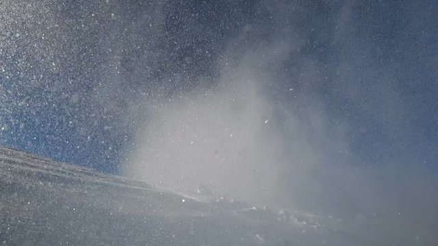 professional rider on a snowmobile jumping up from snow storms. right to left, against a blue sky in a mountain valley. super slow motion video. high quality