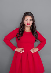 Happy plus size woman in red dress smiling on gray