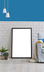 Frame and picture in the room with blue armchair lamp and vase of plant, book style. White ceramic and blue wall background.