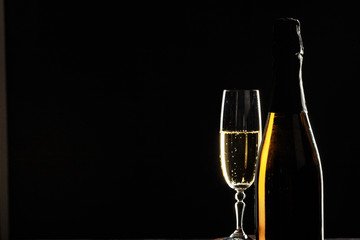 bottle of champagne and glasses over dark background