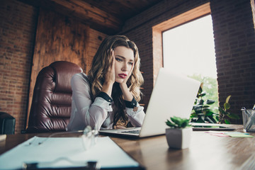 Low below angle view of nice attractive clever smart intelligent sad minded wavy-haired lady professional executive manager holding hands on cheeks at work place station