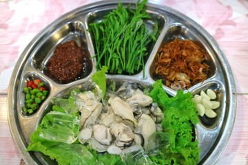 Oysters with herbs, fried sliced garlic, chilli and the dipping spicy sauce. Thai style seafood. Selective focus. Food concept.