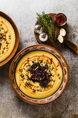 Authentic Greek Fava recipe, Middle Eastern yellow lentil soup with caramelized onions, paprika and capers. vegan healthy food in clay pots on the stone table