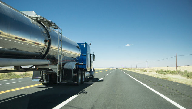 truck with a silver tank trailer passing a passenger car on a highway