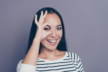 Close-up portrait of her she nice cute attractive lovely positive cheerful optimistic straight-haired lady in striped pullover sweater showing like glasses one eye isolated over gray pastel background