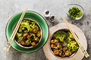 Basmati rice with tofu in General Tso sauce and steamed broccoli. full healthy vegetarian lunch or dinner on a stone table