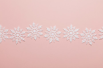 White glitter snowflake composition on a pastel pink background