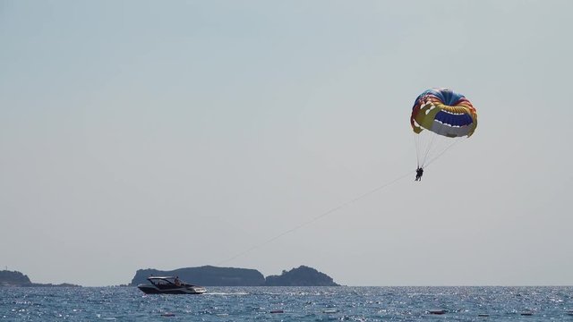 Parasailing behind a boat couple flies over the sea on a parachute tied a rope to the boat