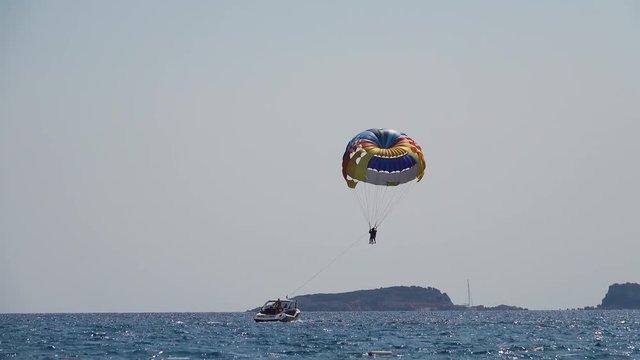 Boat tows a couple on a parachute over the sea, enjoying a parasailing session at the beach
