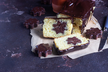 Vanilla pound cake with chocolate glaze served with chocolate biscuit stars on brown paper. Brown stone table. Copy space.