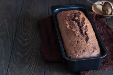 Delicious dark chocolate cake on paper on dark wooden background. Selective focus. Copy space. Christmas or New Year chocolate cake.