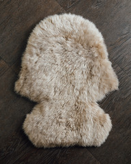 brown sheepskin fur carpet on wooden background