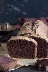 Delicious dark chocolate cake on paper on dark wooden background. Selective focus. Copy space. Christmas or New Year chocolate cake.