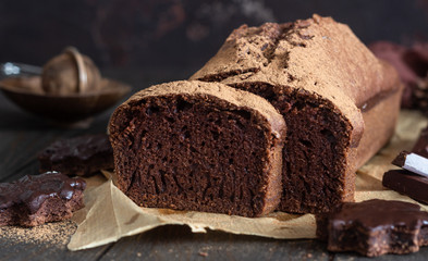 Delicious dark chocolate cake on paper on dark wooden background. Selective focus. Copy space. Christmas or New Year chocolate cake.
