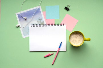 Tablet with a stylus on a green background.A Cup of coffee, headphones, photo.