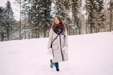 Fototapeta na wymiar Portrait of young beautiful woman playing with snow in winter park