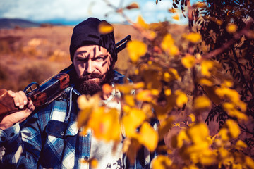 Bearded hunter huntering. Hunting period, autumn season. Hunter with a hunting gun and hunting form...