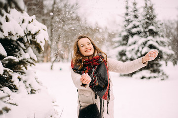 Fototapeta na wymiar Portrait of young beautiful woman playing with snow in winter park