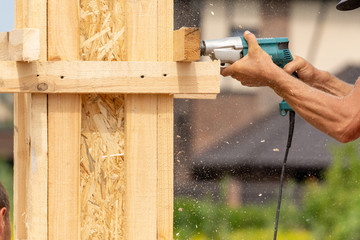 Close up cropped photo of electric instrument in worker hand. He using drill tool to make hole in...