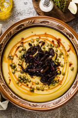 Authentic Greek Fava recipe, Middle Eastern yellow lentil soup with caramelized onions, paprika and capers. vegan healthy food in clay pots on the stone table