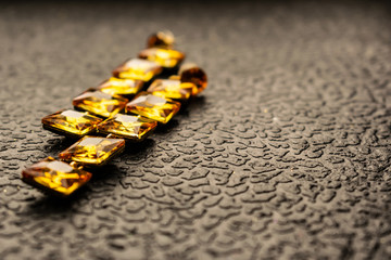 Beautiful and fashionable jewelry and accessories for women. Yellow, orange stones with square stones on dark and wood textured background. Mustard bright rhinestones on a Gold metal base. Interesting